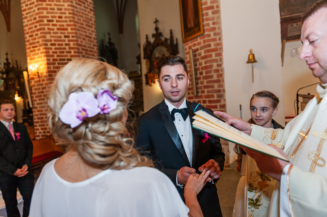 Pan Młody zakłada obrączkę Pannie Młodej w kościele w Pucku podczas ślubu